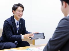 端末を使って説明する営業マン